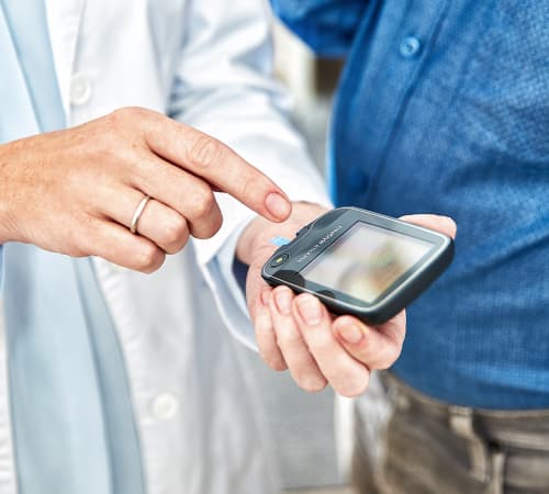 A picture of a doctor holding a glucose monitor in his hand.